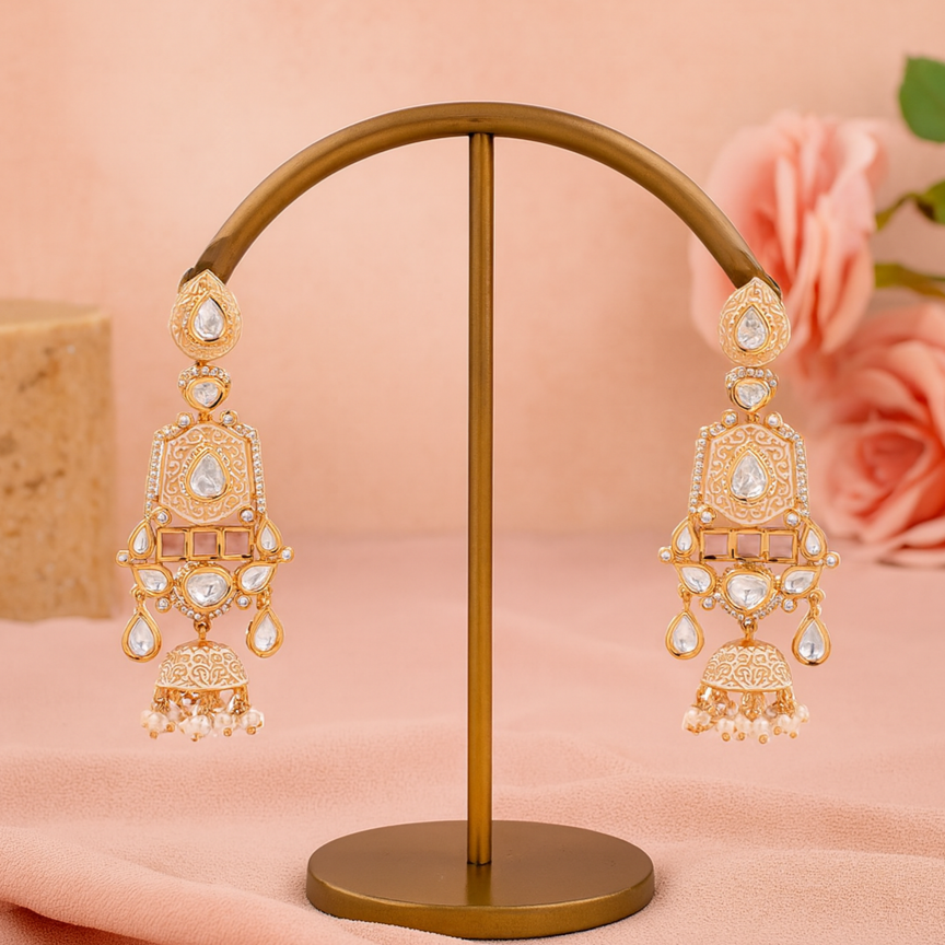 Gold earrings on a stand with a soft pink background