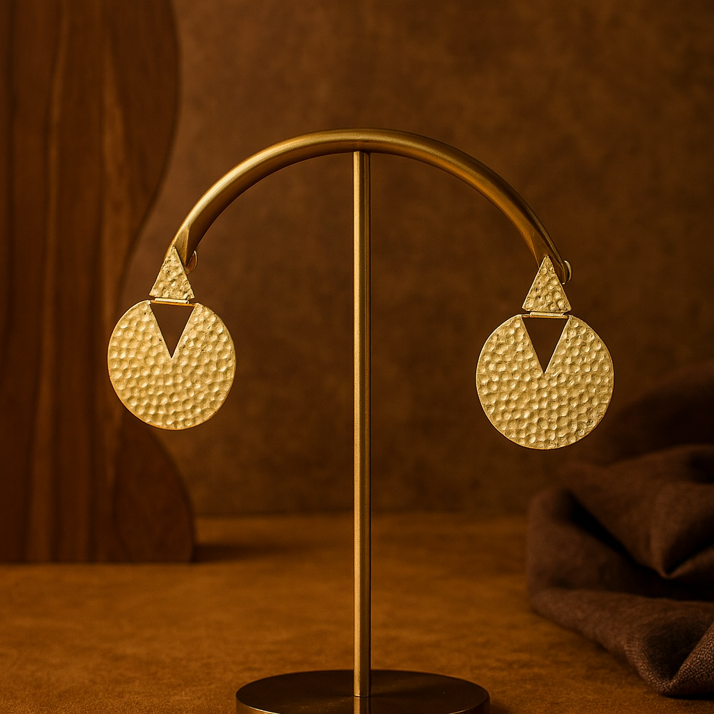 Gold earrings on a stand against a brown background