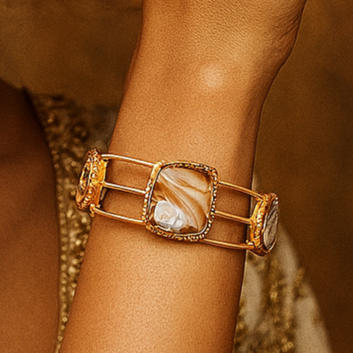 Woman wearing a gold bracelet against a warm brown background