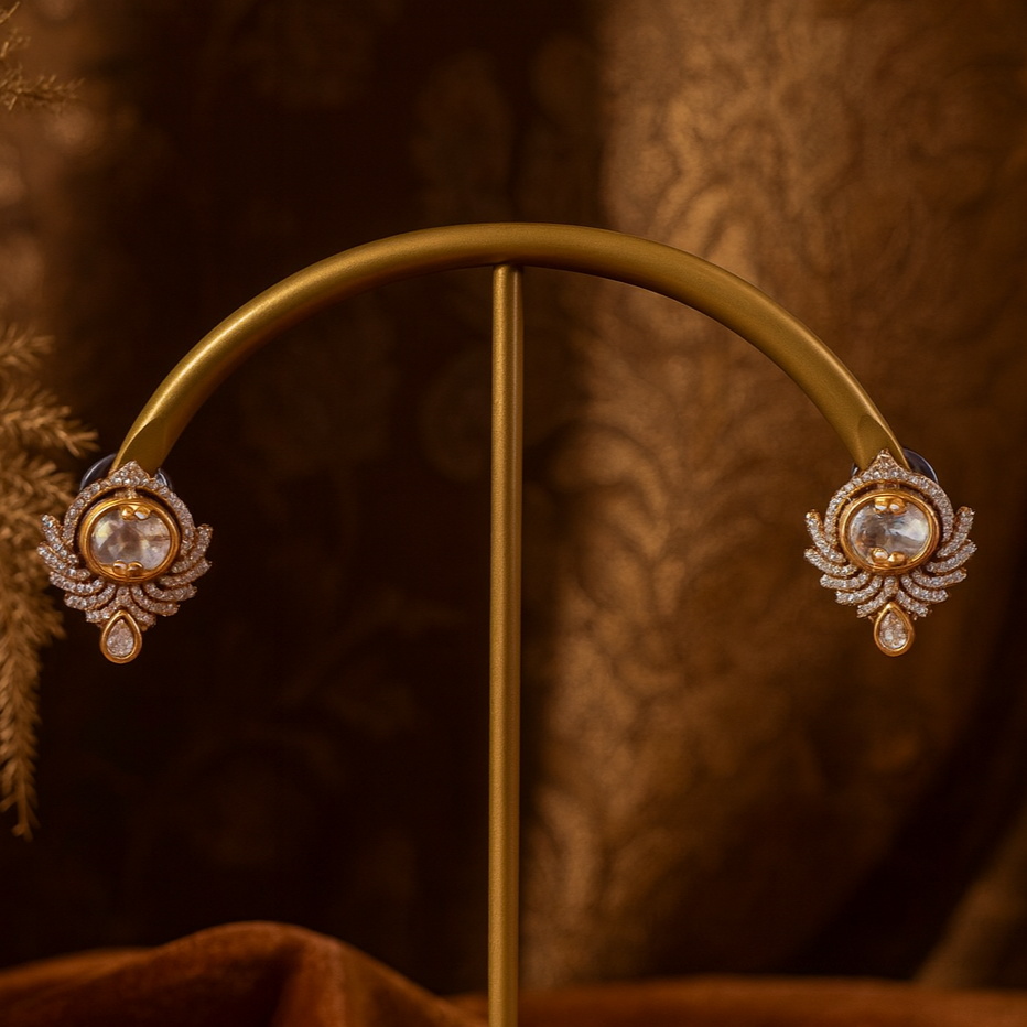Gold earrings with gemstones on a gold stand against a brown textured background