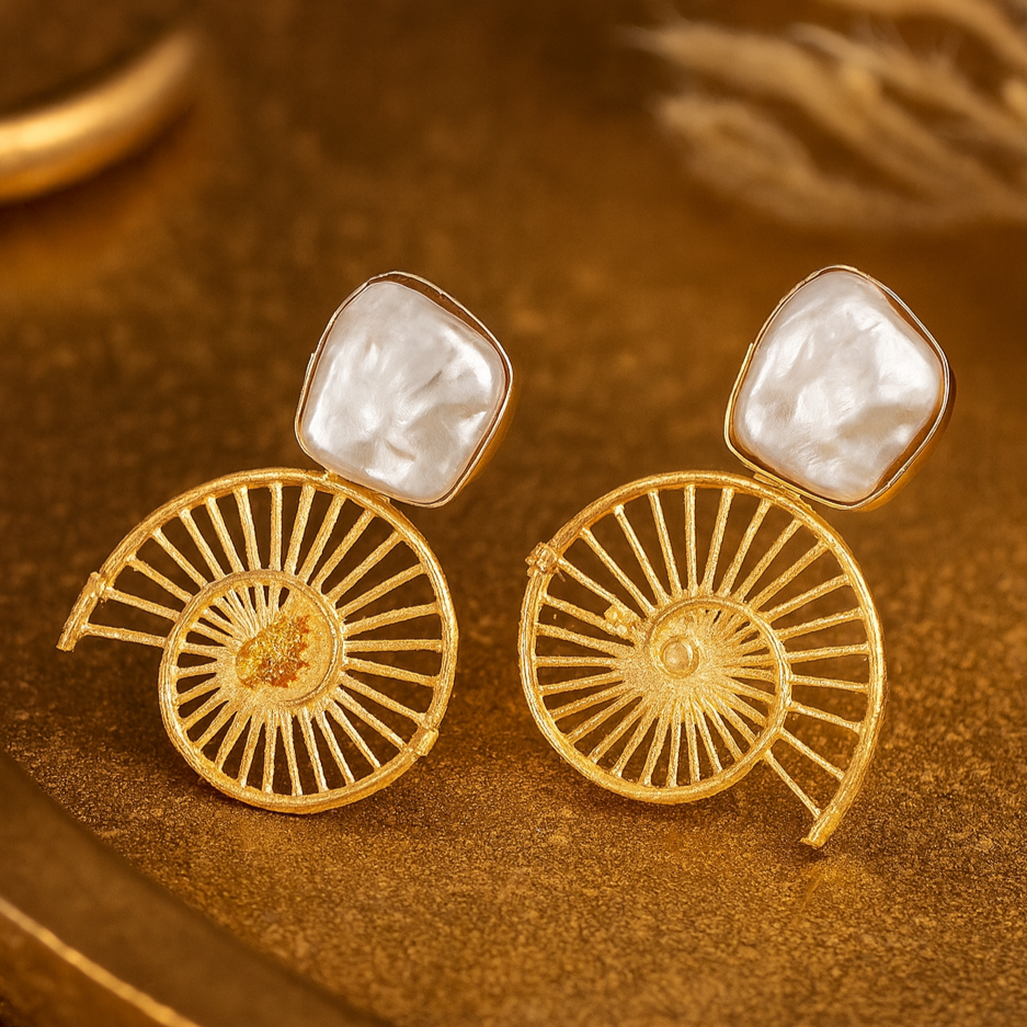Gold earrings with intricate designs on a brown surface