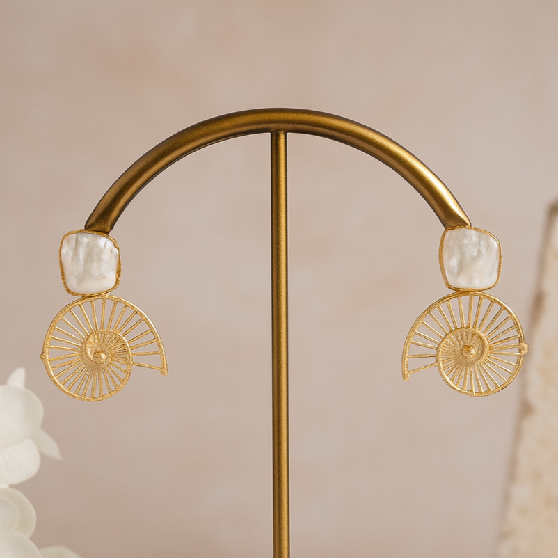 Gold earrings on a stand with a soft beige background