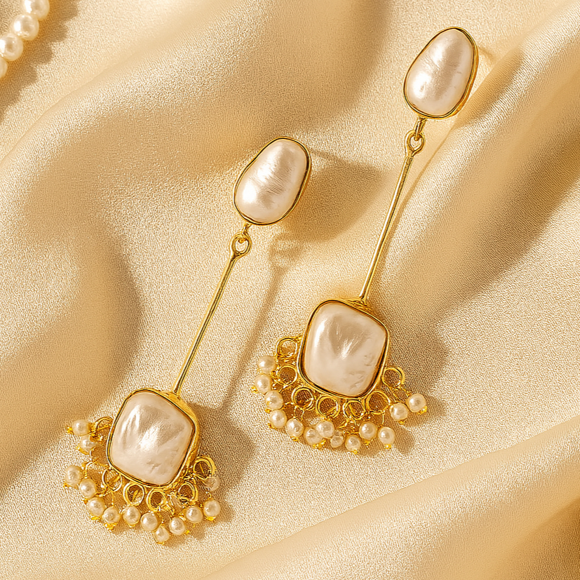 Gold earrings with pearl drops on a beige fabric background