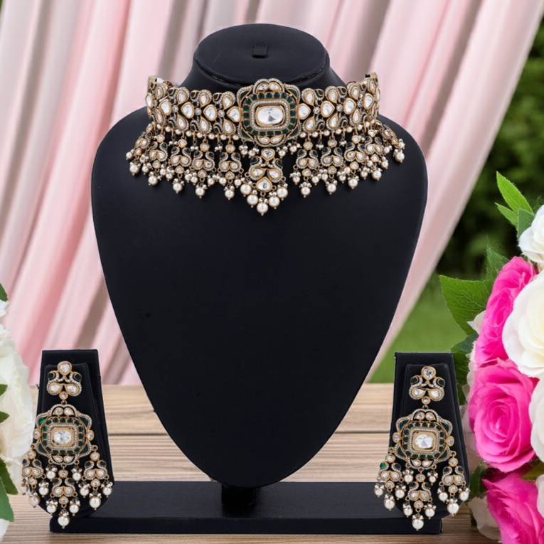 Ornate necklace and earrings set on a black stand with pink and white flowers in the background