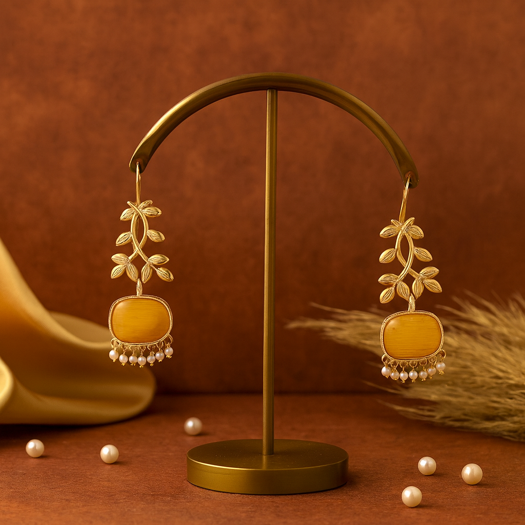 Gold earrings with yellow stones on a brown stand against a brown background