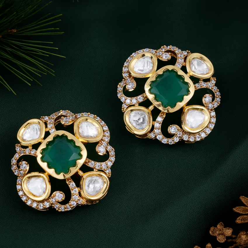 Pair of gold earrings with green and white stones on a dark green background