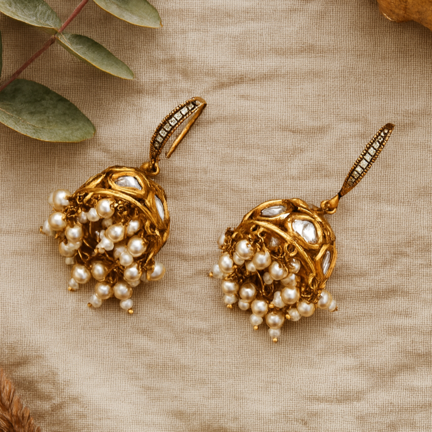 Gold earrings with pearls on a beige fabric background