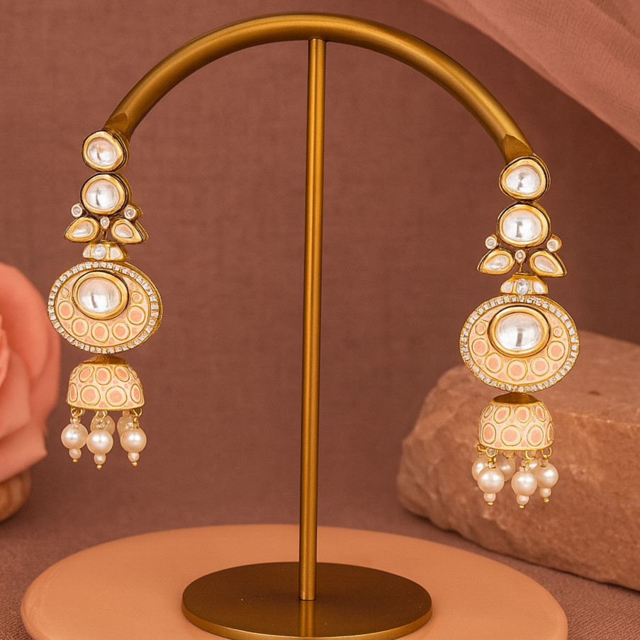 Gold earrings on a stand with a soft pink background