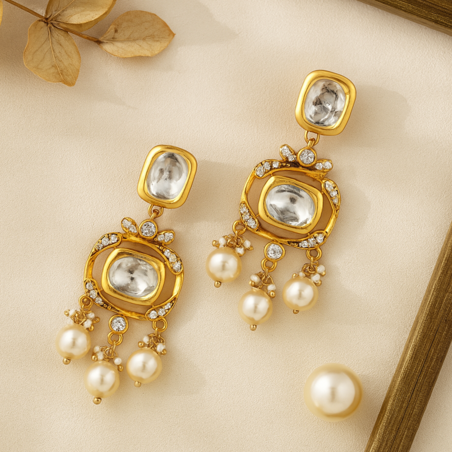 Gold earrings with pearls and crystals on a beige surface