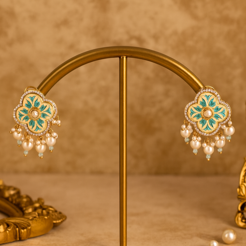 Decorative earrings on a gold stand with a decorative box on a beige background