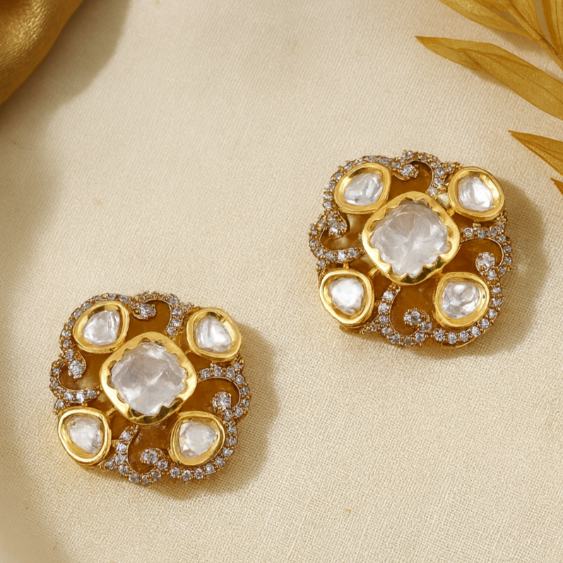Gold earrings with gemstones on a beige fabric background