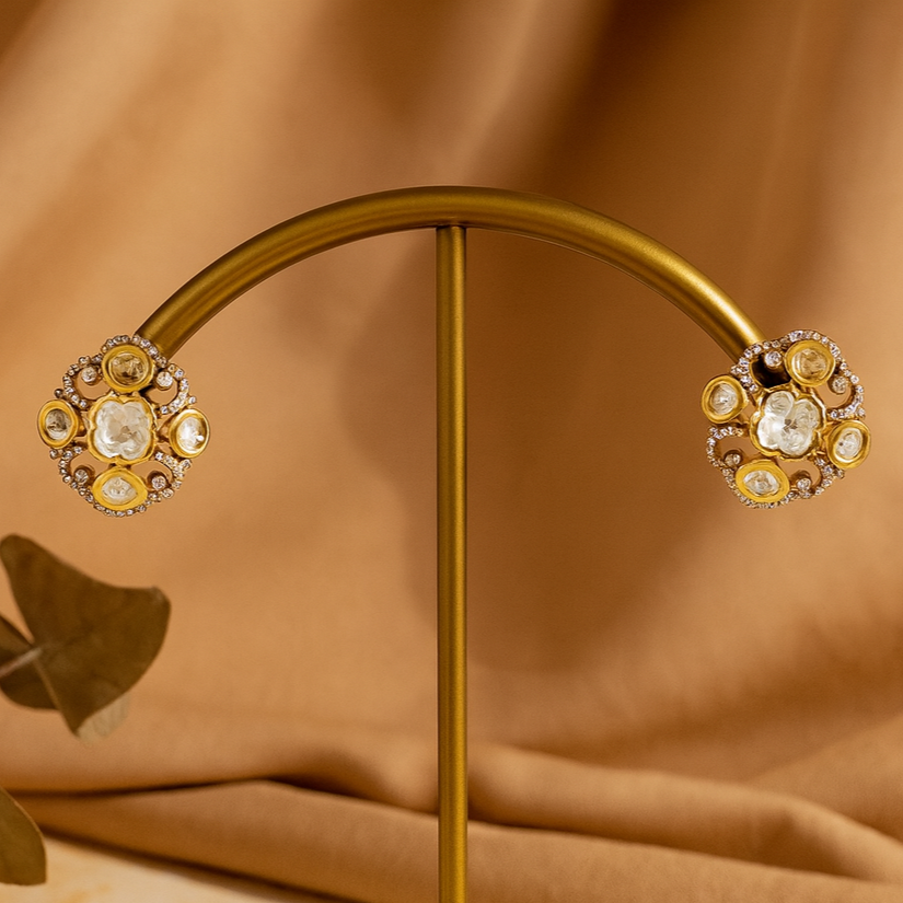 Gold earrings on a stand with a brown fabric background