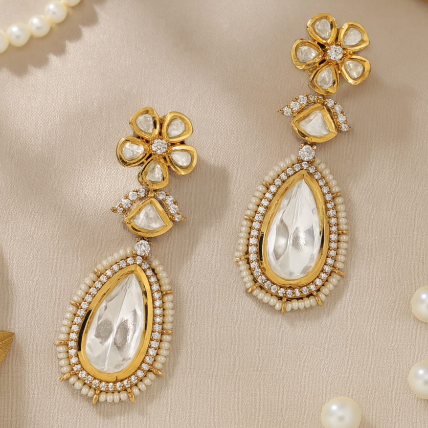 Gold and pearl earrings on a beige fabric background