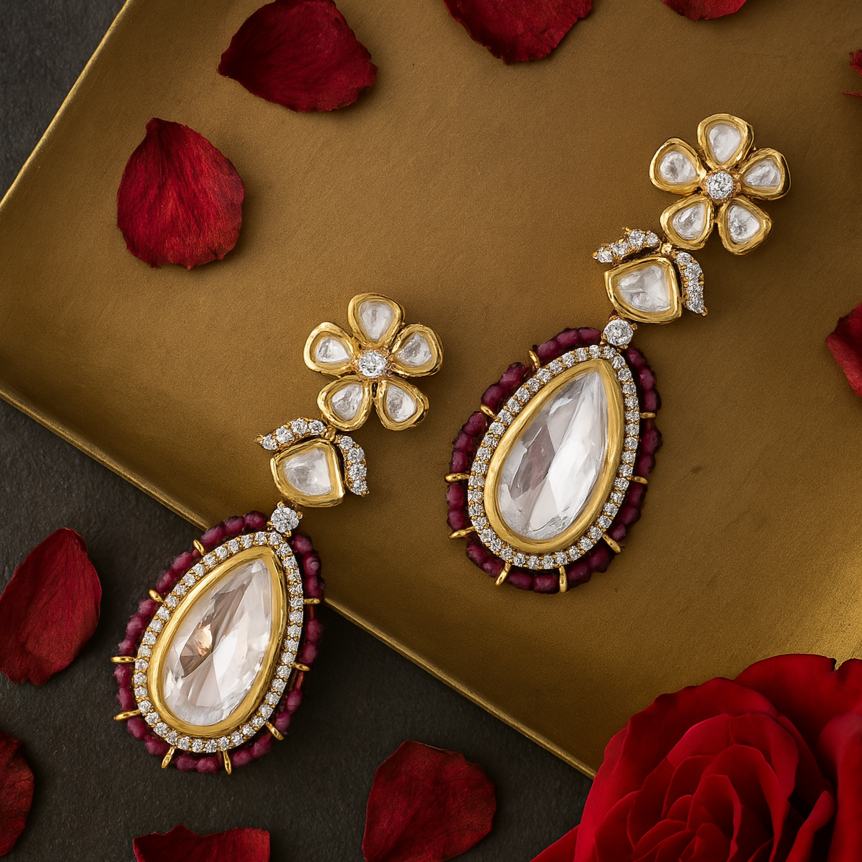 Gold and red earrings on a gold tray with red rose petals