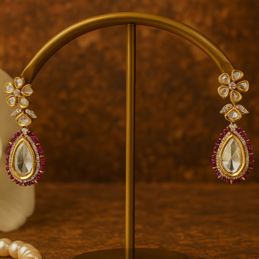 Gold earrings with gemstones on a gold stand against a brown background