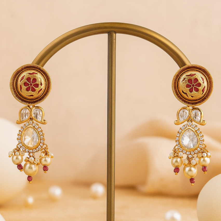 Gold earrings with floral designs and pearl beads on a beige background