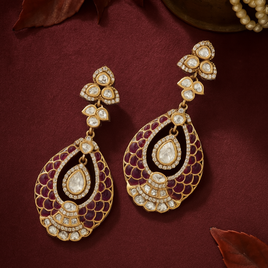 Ornate gold earrings with gemstones on a maroon background