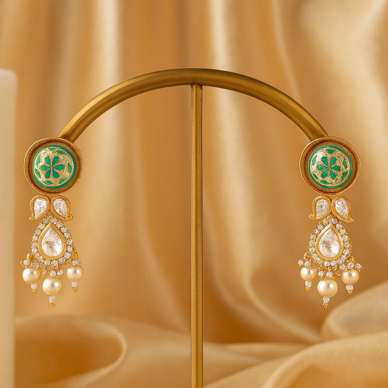 Gold earrings with green gemstones on a gold stand against a beige fabric background