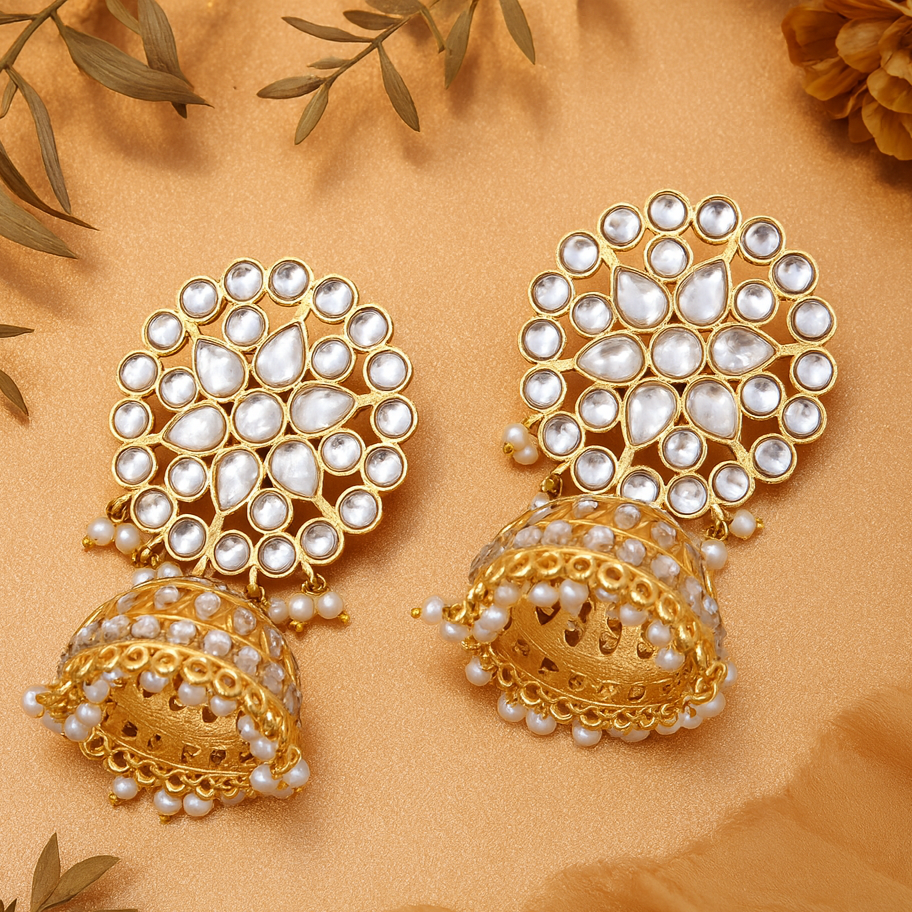 Gold and pearl earrings on a beige background with leaves.
