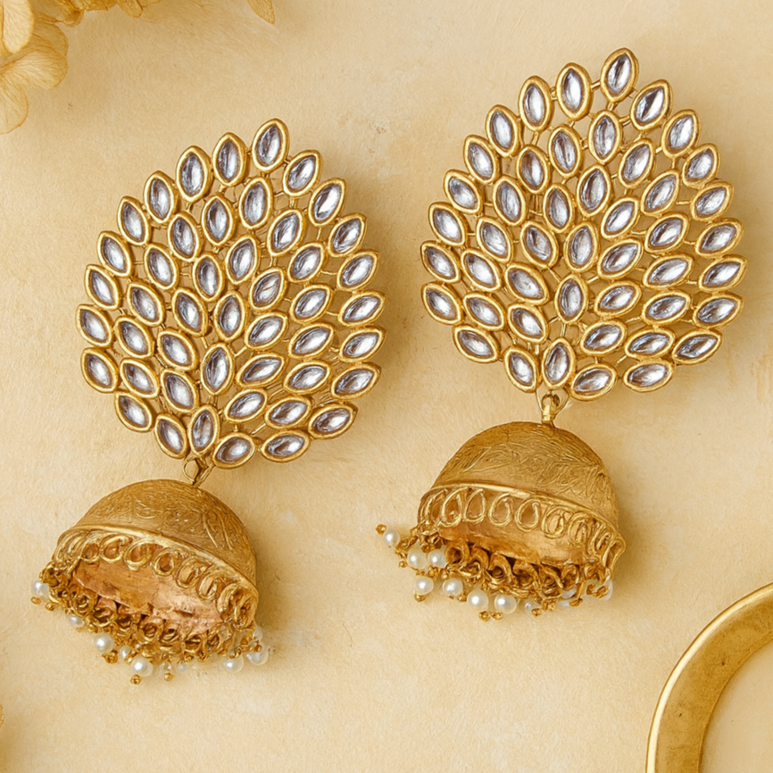Gold earrings with intricate design on a beige background