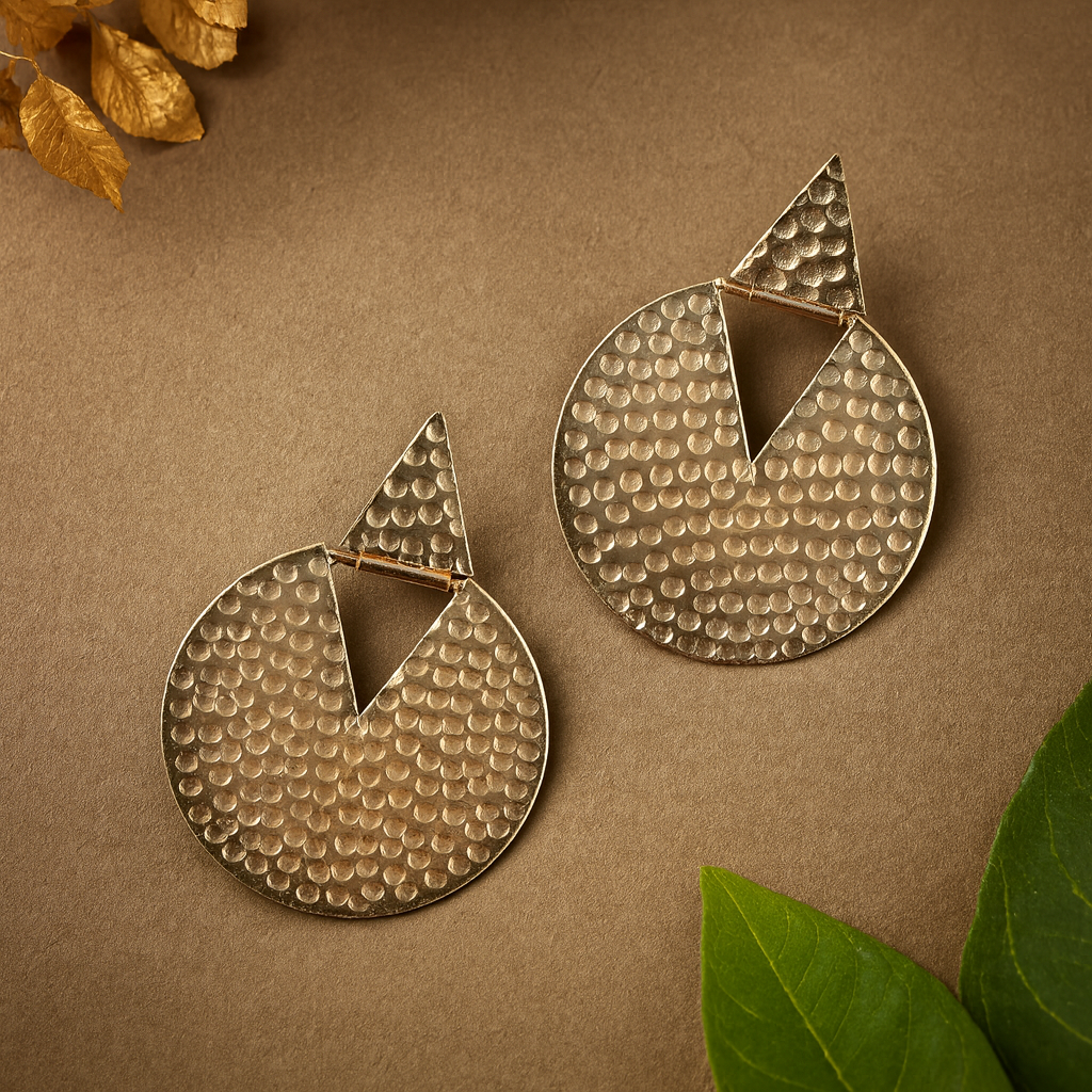 Pair of gold earrings on a brown background with leaves