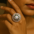 Woman wearing a large, ornate ring with a neutral background