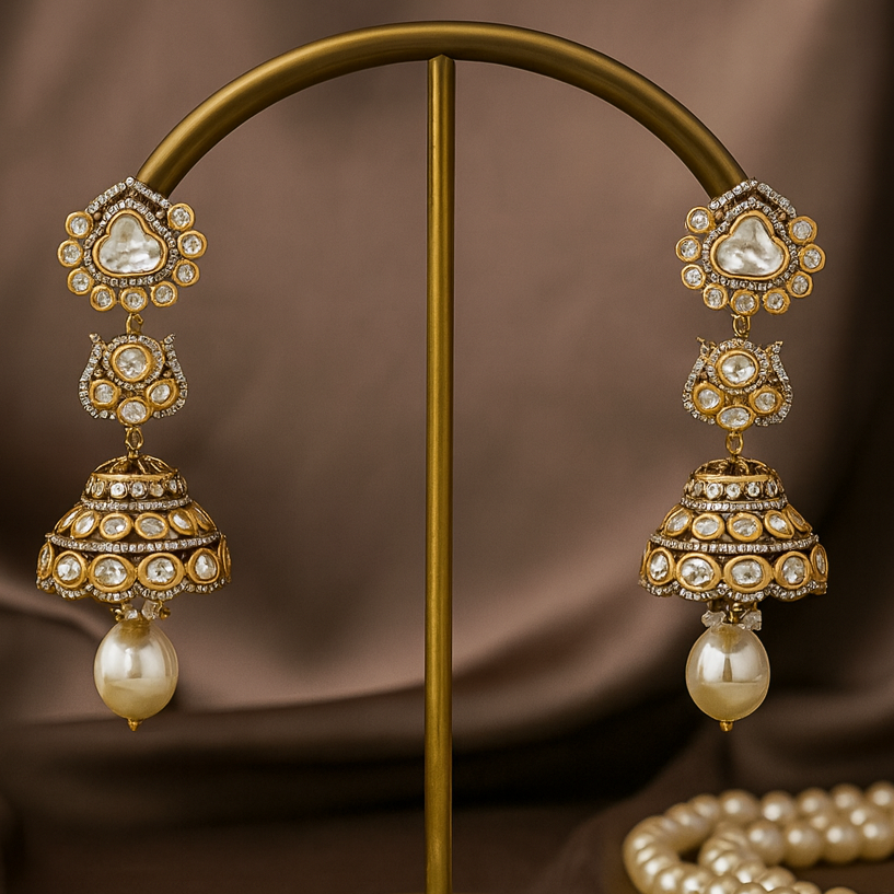 Ornate earrings with pearls on a gold stand against a brown background