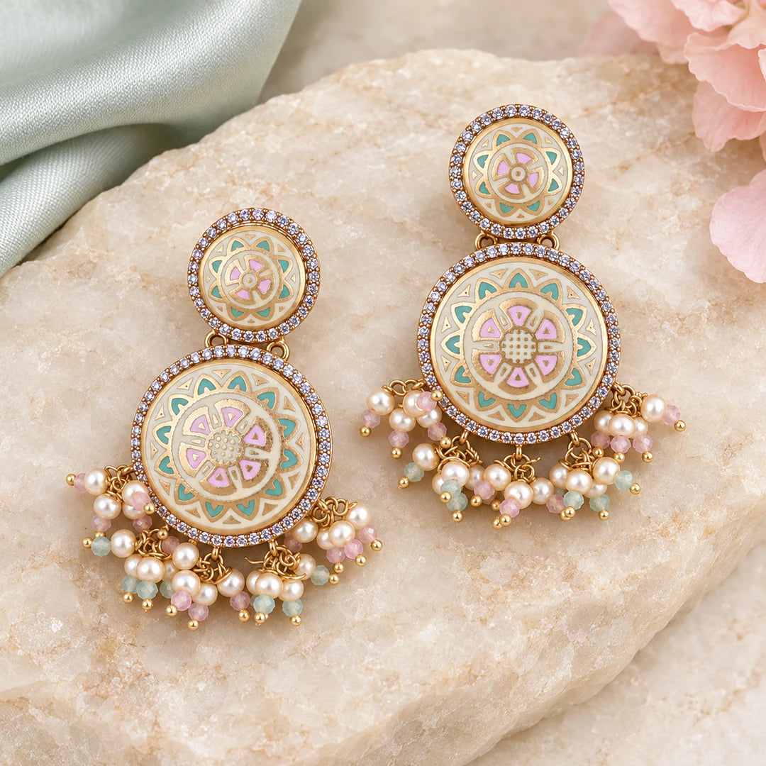 Pair of Kalika ivory, mint and pink floral drop earrings on cream stone beside pale mint silk and blush flowers.