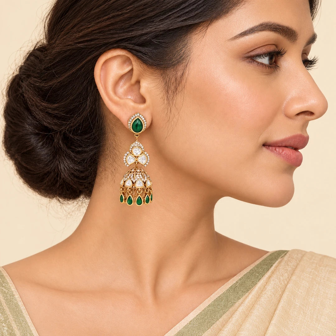 Indian model in an ivory saree with a sage border wearing a vertically hanging Kashika green and gold-tone jhumka earring