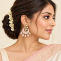 Indian model in an ivory saree with a pink border wearing a Kumud floral chandbali earring, with her hair in a jasmine-adorned bun.