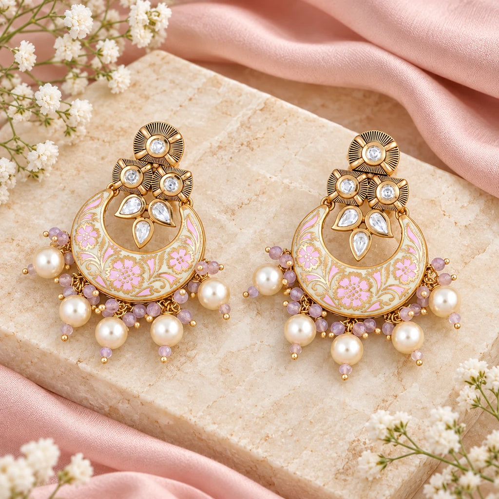 Pair of Kumud ivory and pink floral chandbali earrings with cream pearl-style drops on cream stone beside blush silk and small white flowers.