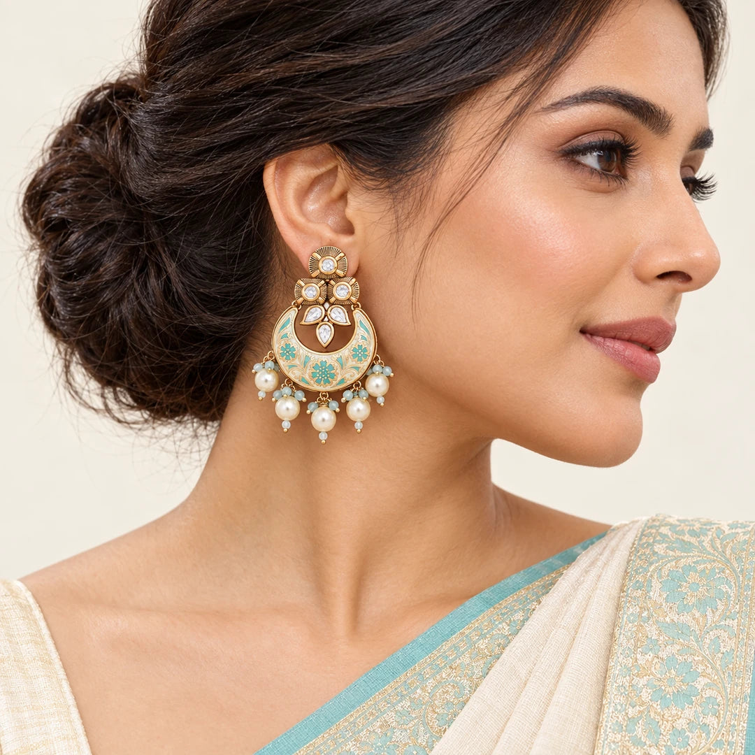 Indian model in an ivory saree with an aqua border wearing a Kumud floral chandbali earring with cream pearl-style drops.
