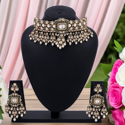 Ornate necklace and earrings set on a black stand with pink and white flowers in the background