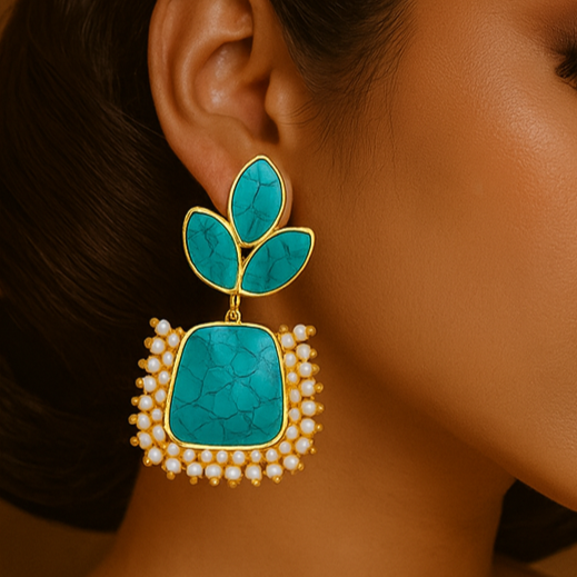 Woman wearing turquoise earrings with gold accents against a warm brown background