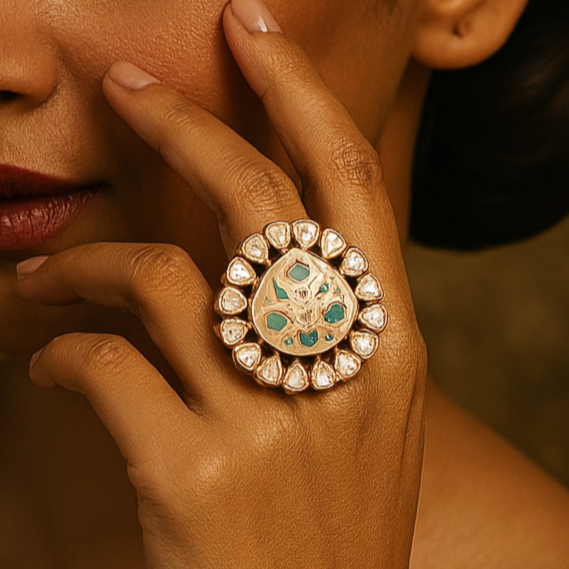 Woman wearing a gold ring with gemstones, touching her face against a warm-toned background