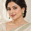 Indian model in an ivory saree with a sage border wearing Aabha green teardrop earrings.