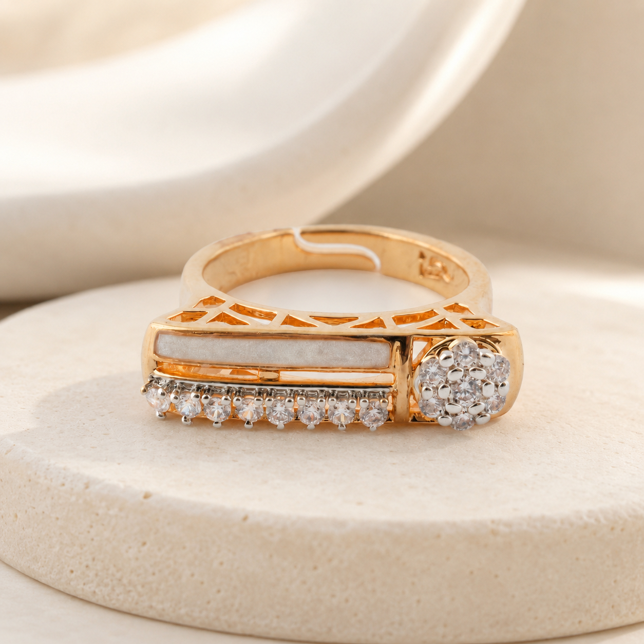 Gold-finish diamond-look statement ring displayed on a neutral luxury background