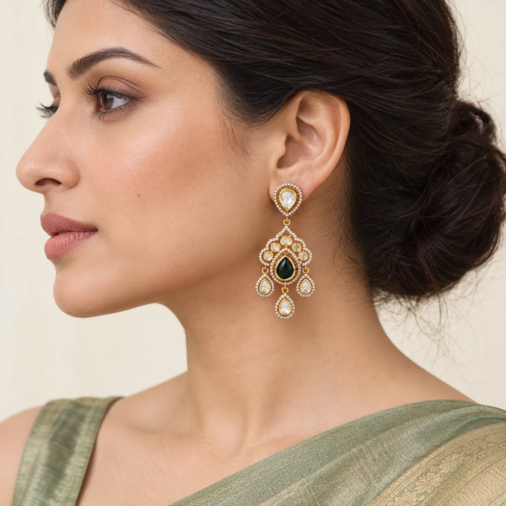 Model in side profile wearing an Advika gold-finish green Kundan chandelier earring with three clear teardrop drops.