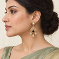 Model in side profile wearing an Advika gold-finish green Kundan chandelier earring with three clear teardrop drops.
