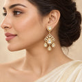 Model in side profile wearing a single Advika gold-finish Kundan chandelier earring with clear stones and three teardrop drops.