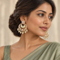 Indian model in a sage saree wearing ivory and mint chandbali earrings with clear-stone floral studs and pearl-look drops.