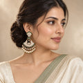 Indian model in an ivory saree with a sage border wearing a Chandrika green chandbali earring with pearl-look drops.