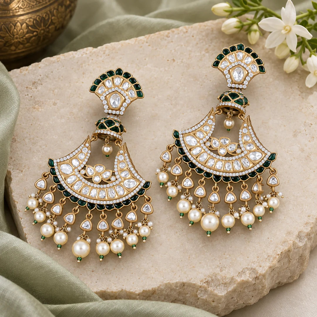 Pair of Chandrika green chandbali earrings with clear stones, gold-tone detailing and pearl-look drops against a black background.