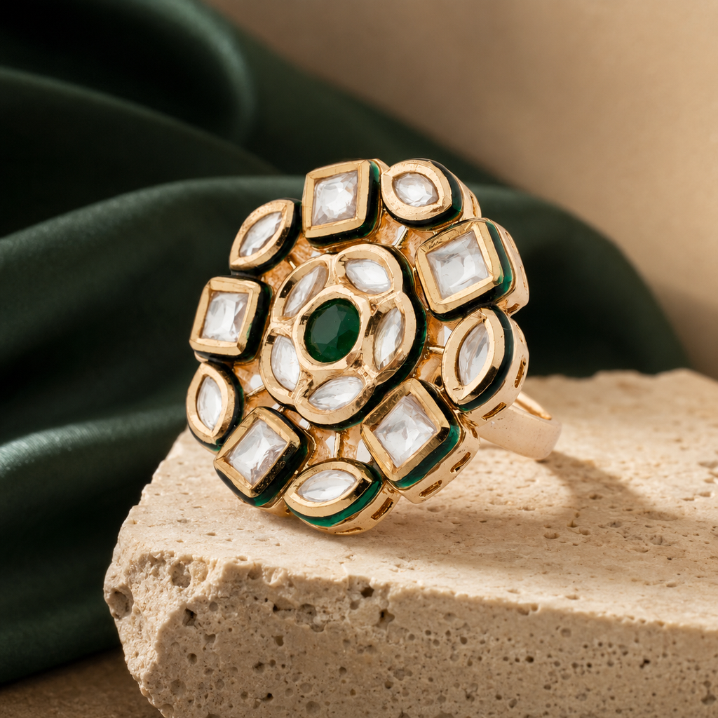 Gold-finish artificial finger ring with clear stones and green centre, angled view