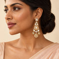 Indian model in a peach saree wearing a long antique gold-tone chandelier earring with clear stones and three engraved drops.