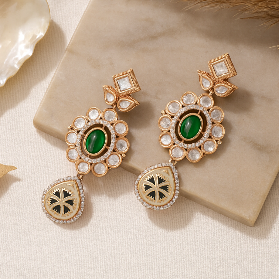 Ornate gold earrings with green gemstones on a beige surface