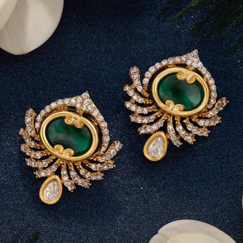 Pair of gold and green gemstone earrings on a dark blue background