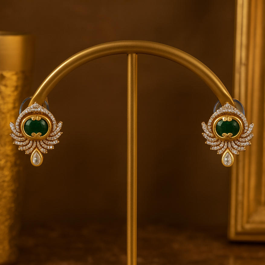 Gold earrings with green gemstones on a gold stand against a brown background