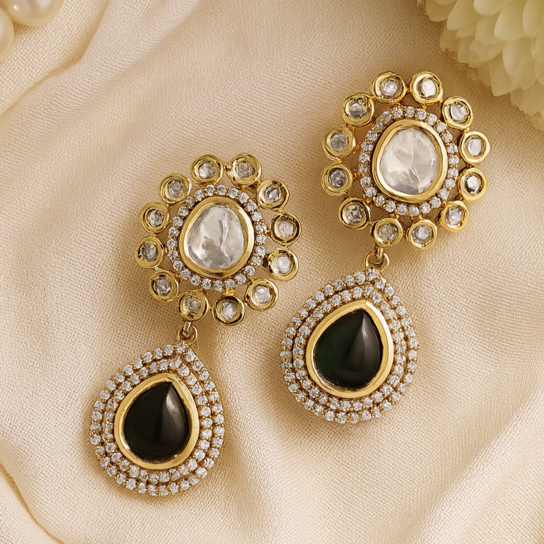 Gold and black earrings on a beige fabric background