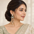 Indian model wearing a Gulika green chandelier earring with clear stones and pearl-look drops, styled with an ivory and sage saree.